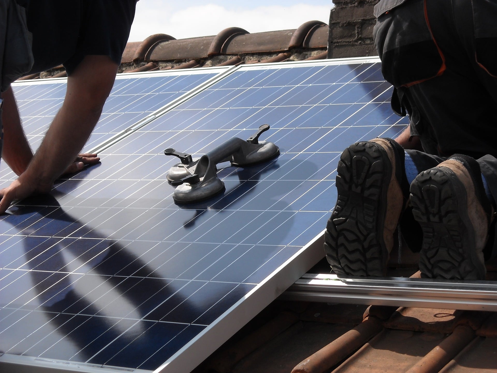 Deux ouvirers installant des panneaux solaires sur le toit d'une maison