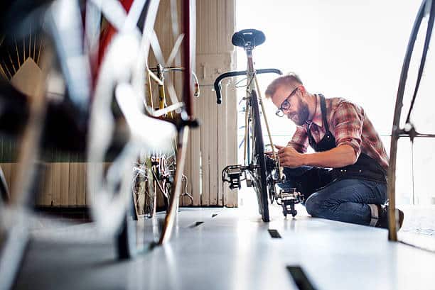 Homme qui répare un vélo dans un garage