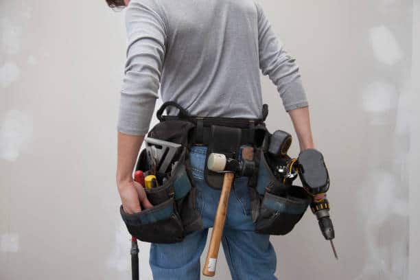 Homme de dos qui porte une ceinture d'outils de bricolage
